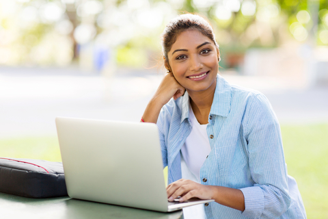 Woman sitting at table with laptop, smiling.