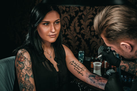 A woman getting a tattoo on her lower arm