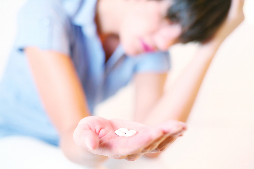 girl in pain with pills in her hand