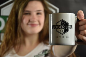 a woman holding a mug that says Sober Joe