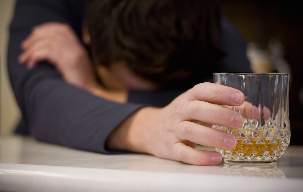 person nursing a glass of alcohol