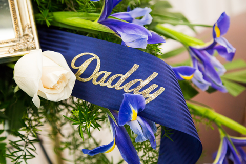 Funeral ribbon with scripted text reading "Daddy", and flowers