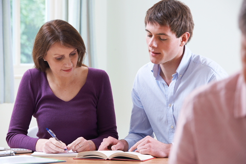 Woman and man at table, writing or studying.