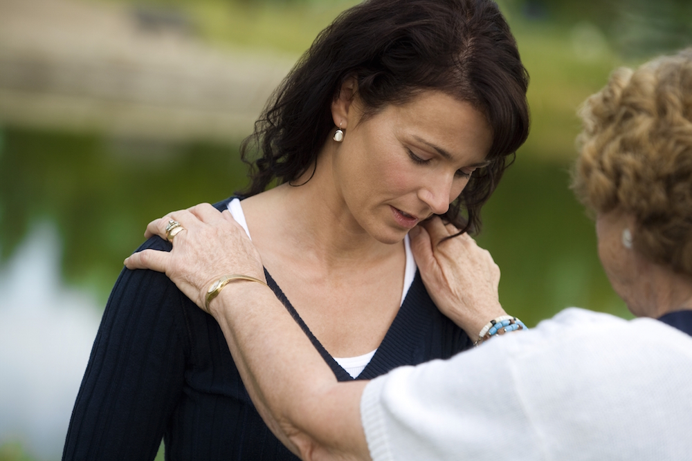 grieving woman being offered support by another woman.