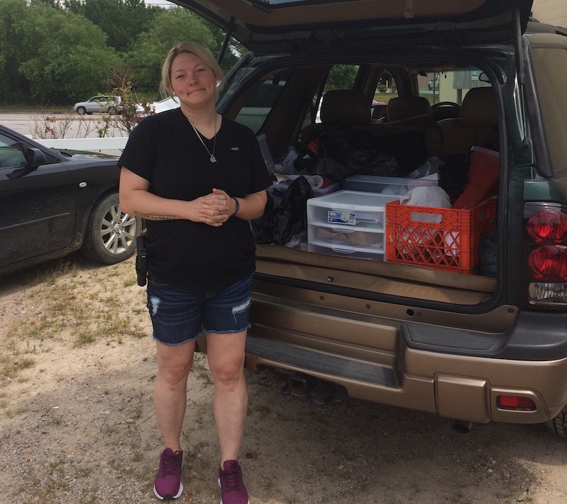 Brandi Tanner stands by the back of her open car, which is full of crates of supplies.