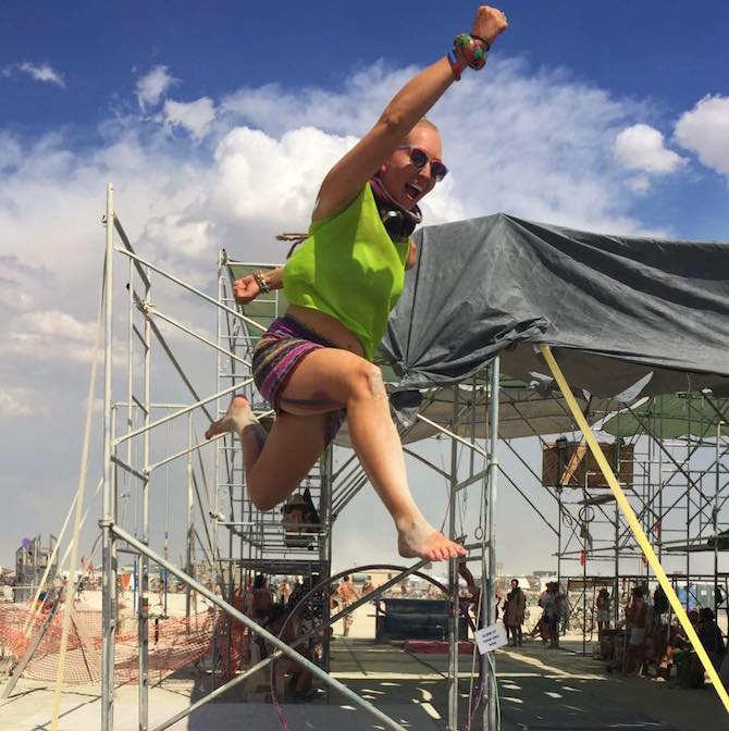 The author, Carrie Hoffman, in mid-air, jumping with arms outstretched and mouth open.