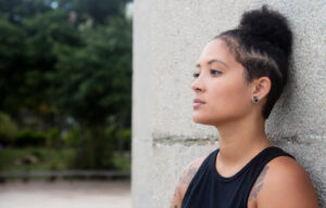 Serious woman with back against wall.