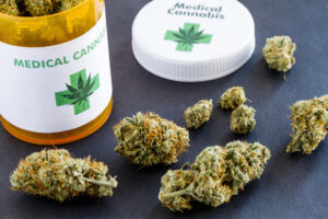 Medical marijuana buds in large prescription bottle with branded cap on black background