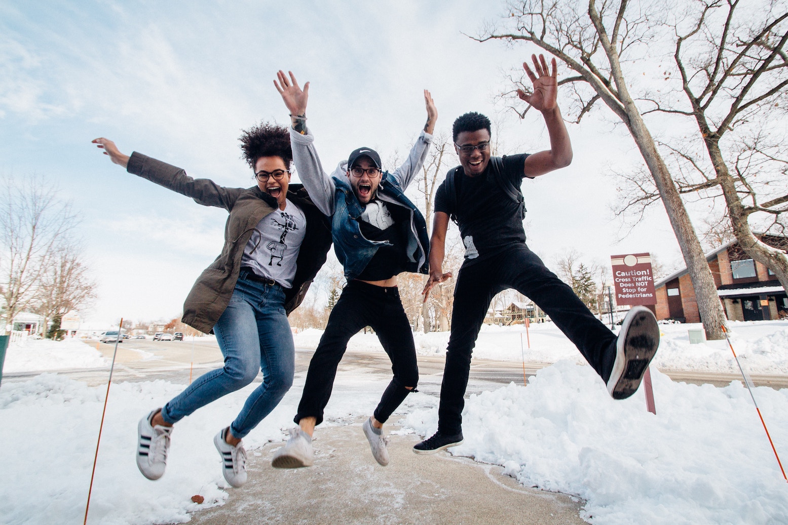 Three people jumping for joy, smiling, arms out.