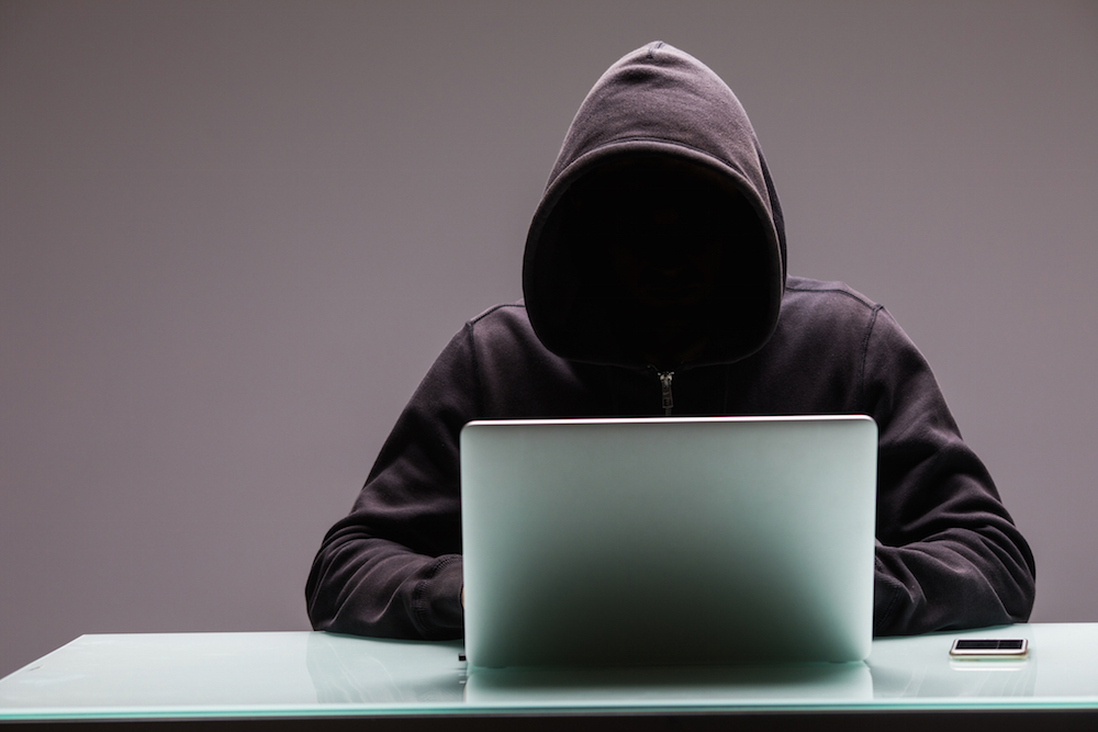 person in a hoodie using a laptop