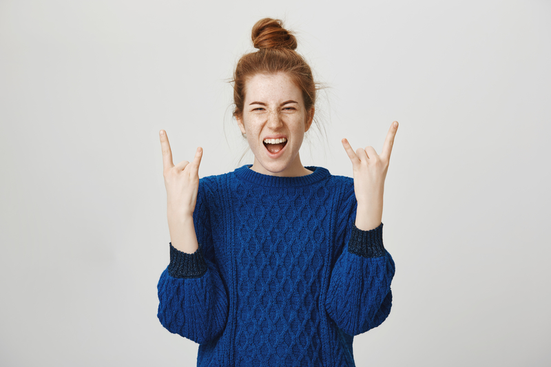 Woman holding up rock n roll signs with both hands.