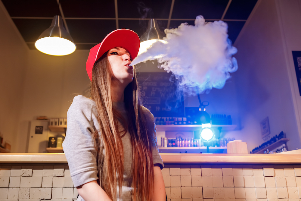 young woman vaping in a smoke shop