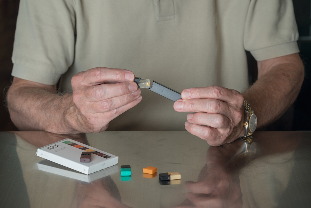 Man putting JUUL nicotine dispenser together with flavor pods.