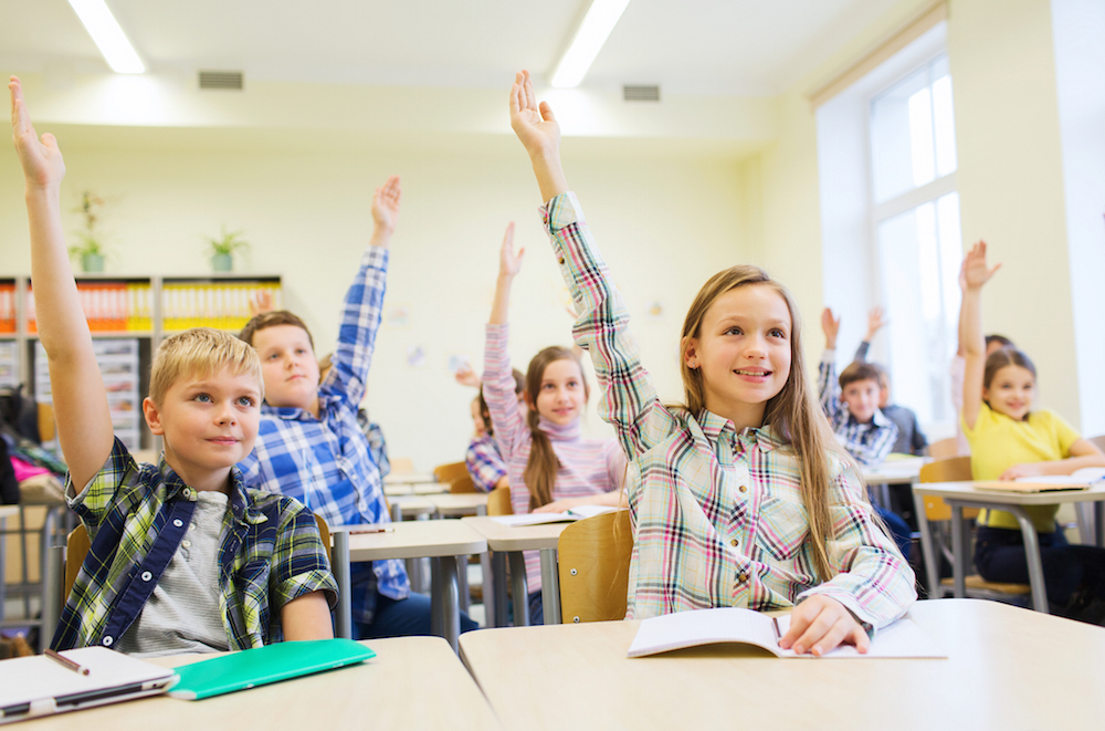kids raising their hands in a classroom