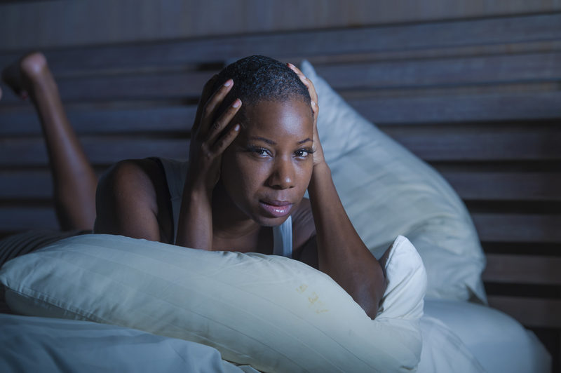 Woman lying in bed looking depressed, head in hands.