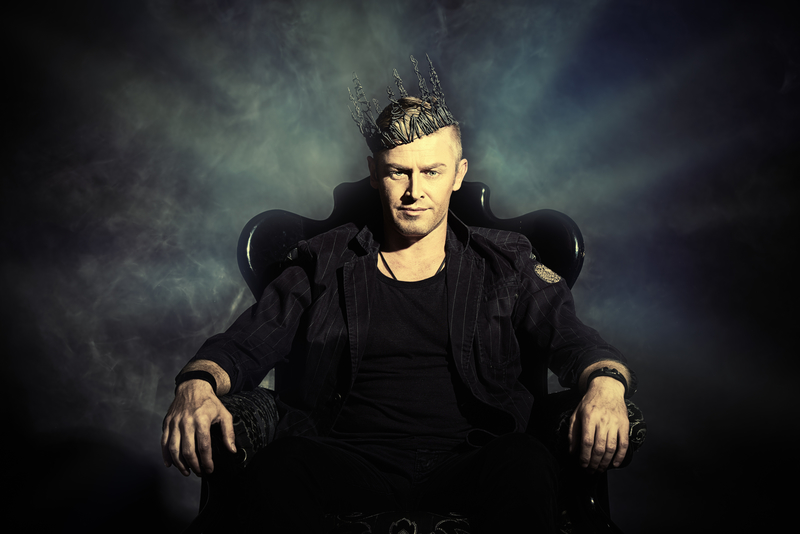 Man sits with crown on his head.