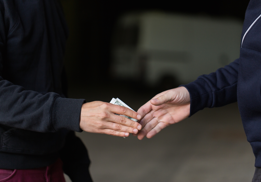 close-up of hands exchanging money for a drug deal