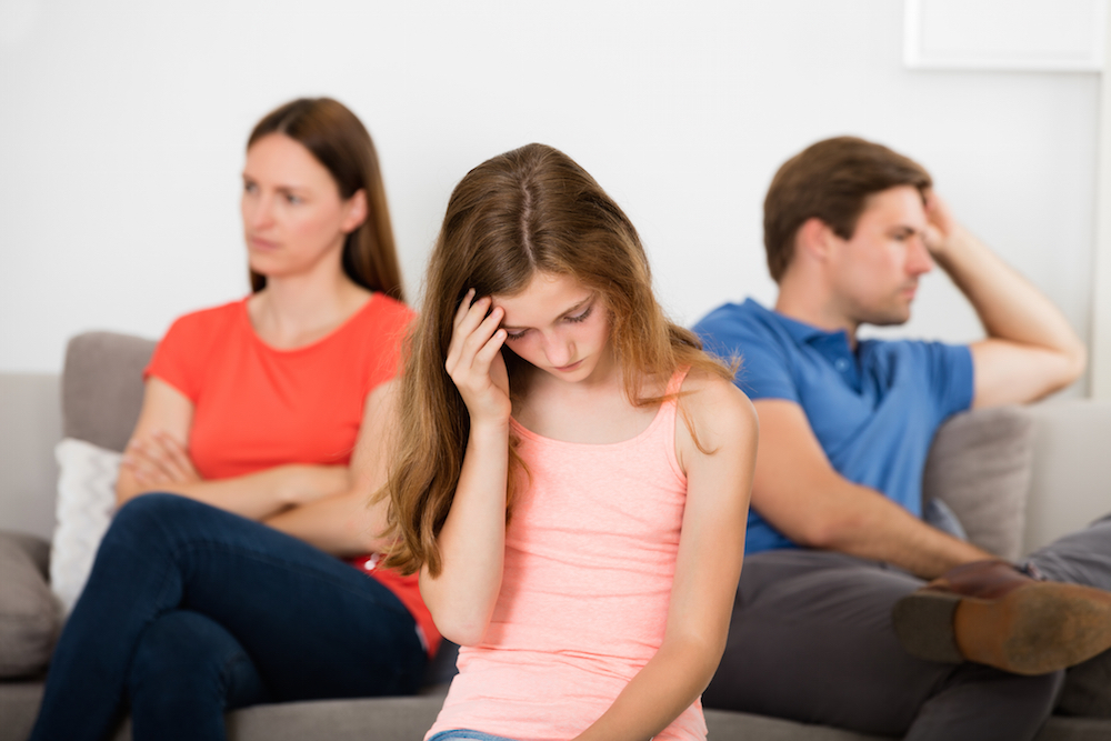 upset teen sitting between mother and father