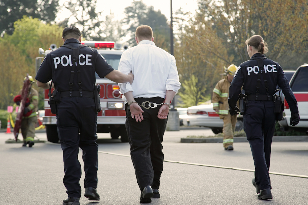 Man under arrest being escorted by two police officers