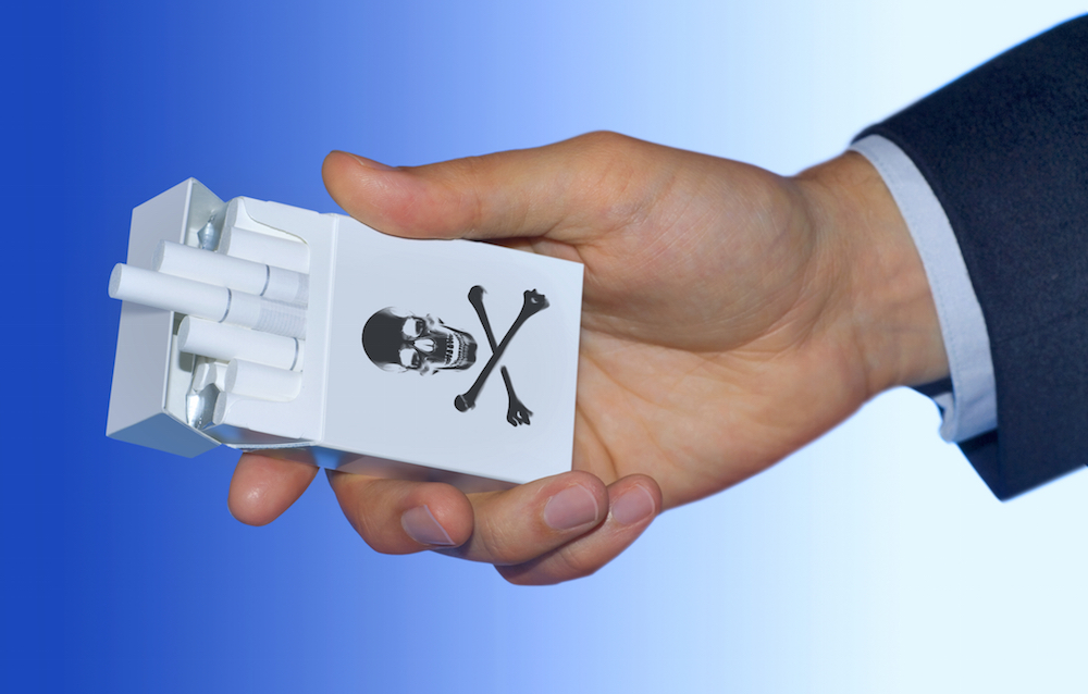 skull and crossbones on pack of cigarettes in a man's hand