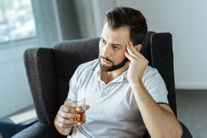 Sad man holding alcoholic drink, rock bottom