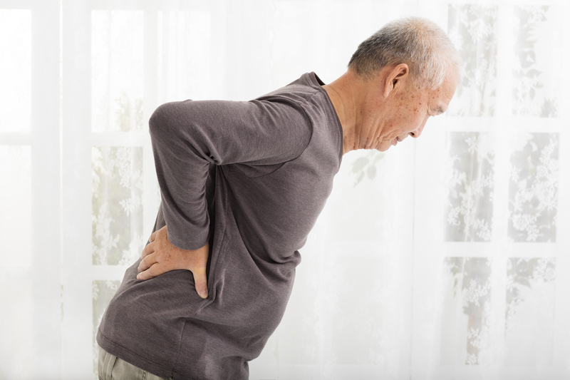 Older man bent over holding his back, chronic pain patients.