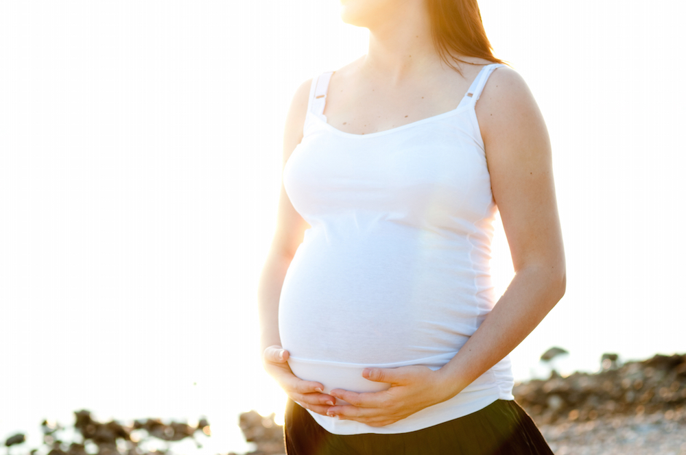 pregnant woman holding her stomach after smoking marijuana.