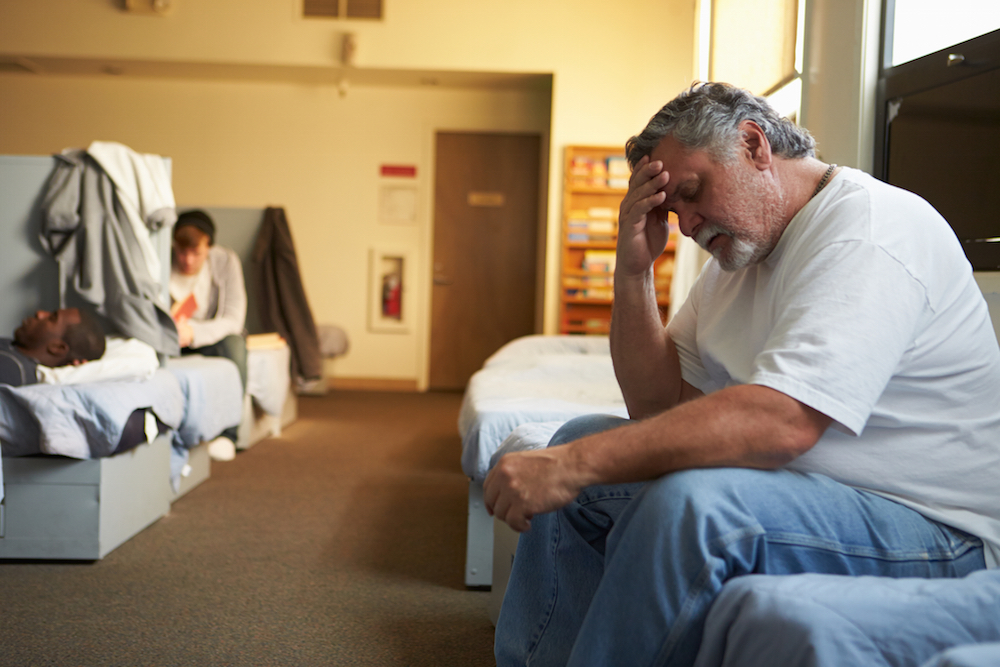 men sitting on their beds inside of a shelter that requires sobriety
