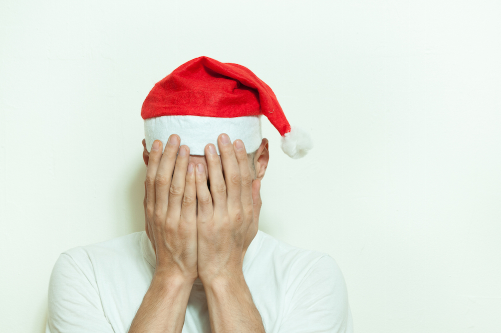 man in Santa hat dealing with holiday stress