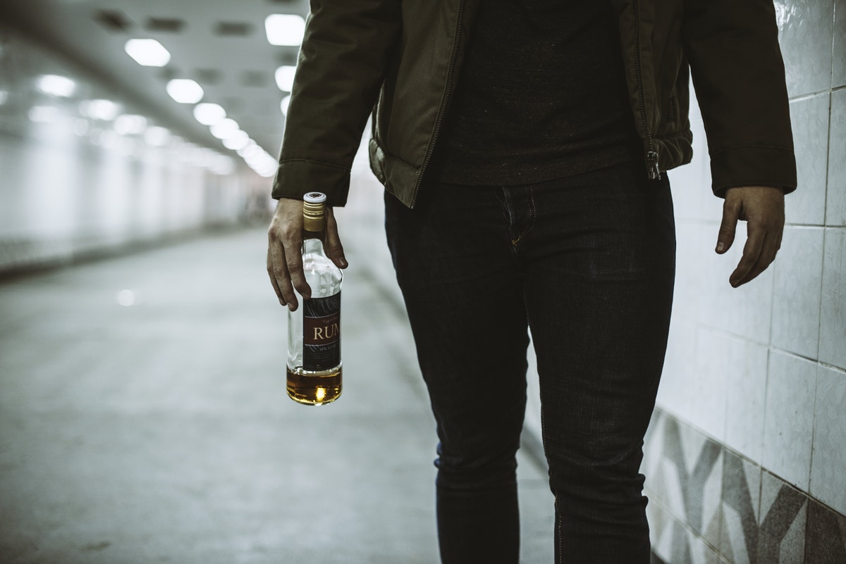 Male body in hall, holding bottle of alcohol, substance abuse and domestic violence