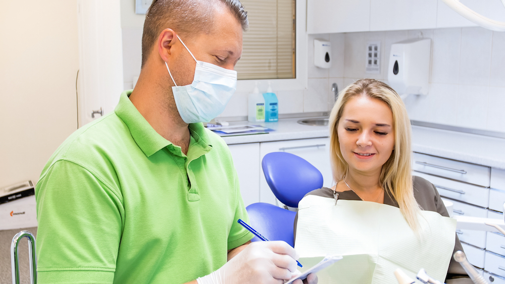 dentist writing opioid prescription to patient