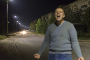 Blurred image of a man screaming at night on an empty street. Buying drugs on Christmas, dope dealer