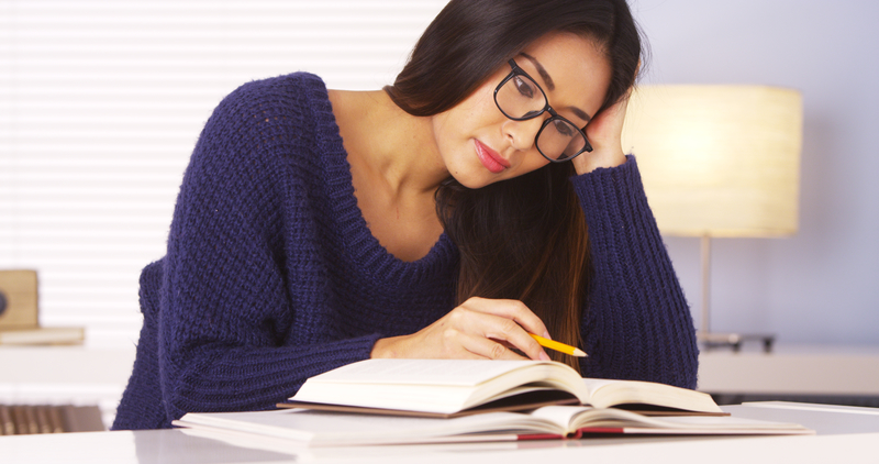 Woman sits, reads addiction book and holds pencil