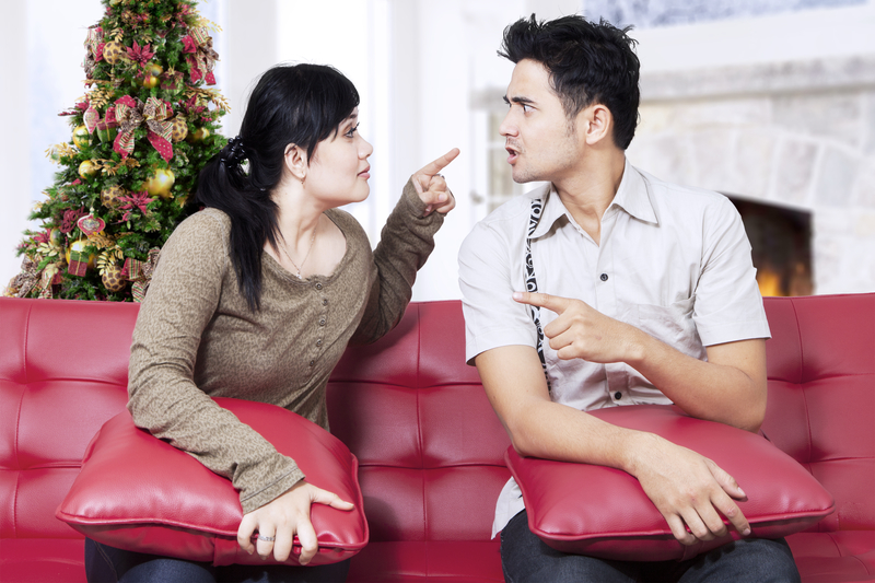 Woman and man argue on a couch in front of Christmas tree; 12-step program at holidays