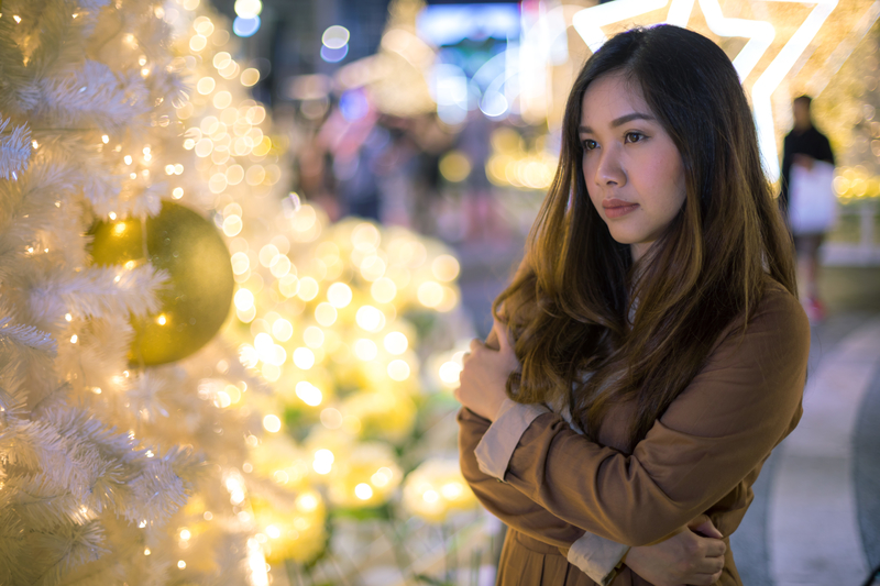 Woman next to holiday decorations, alone and avoiding FOMO Fear Of Missing Out