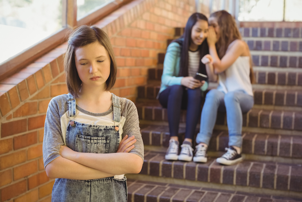 teen girl being bullied by two other teen girl in school