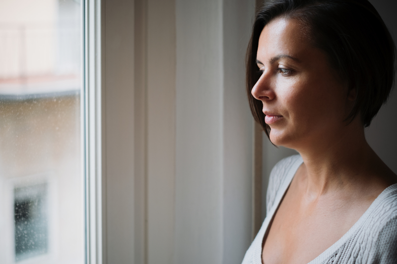 woman wondering about nearby rehabs, looking out the window