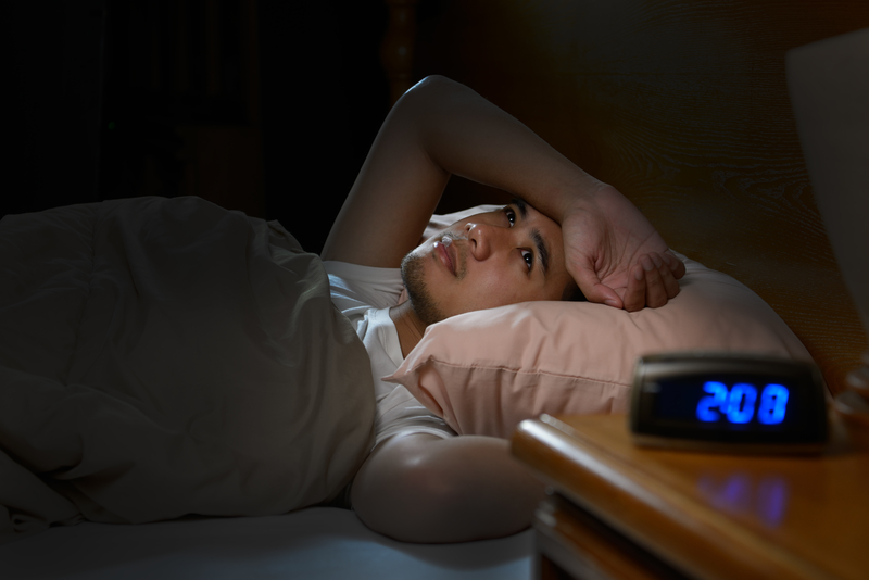 Man lying in bed awake in the dark with digital clock reading 2:08, with sleep problems early recovery