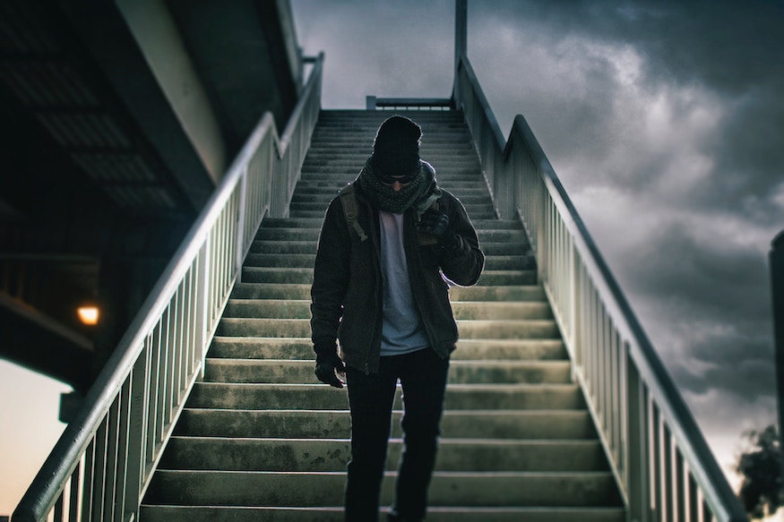 Man walking down staircase outdoors, against cloudy sky