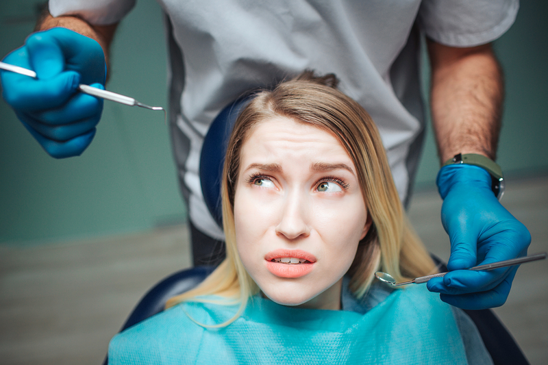 Woman in dentist chair, looking scared, dental phobia in addiction recovery