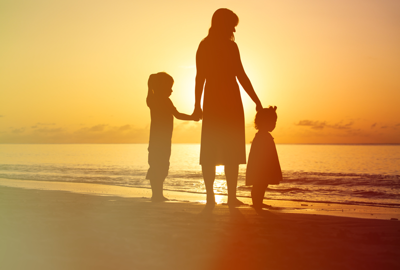 Mother with two children at beach outlined by sunset, mother worrying about losing children because of past drug use