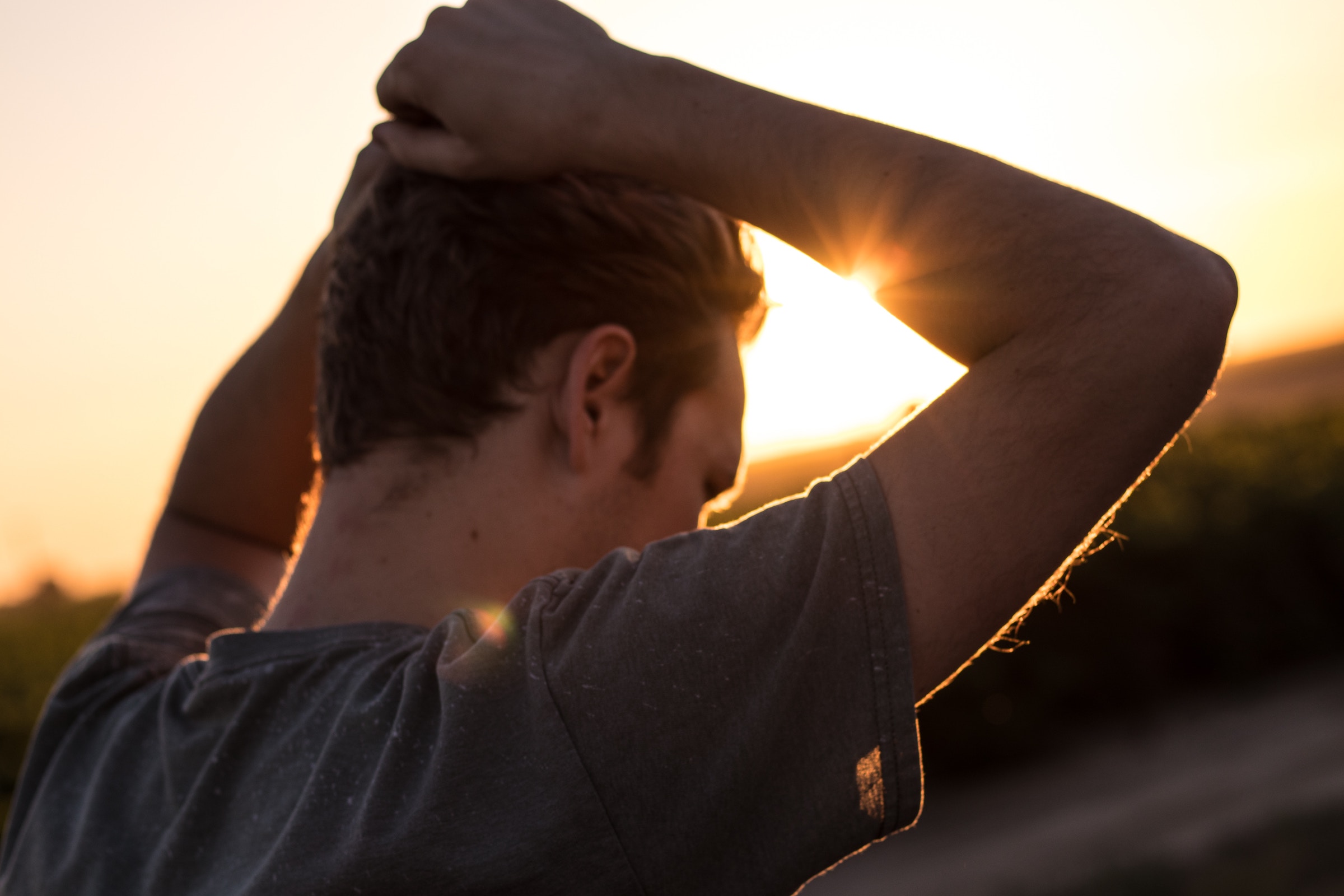 Young man with hands on head, at sunset, pondering life setbacks, relapse prevention