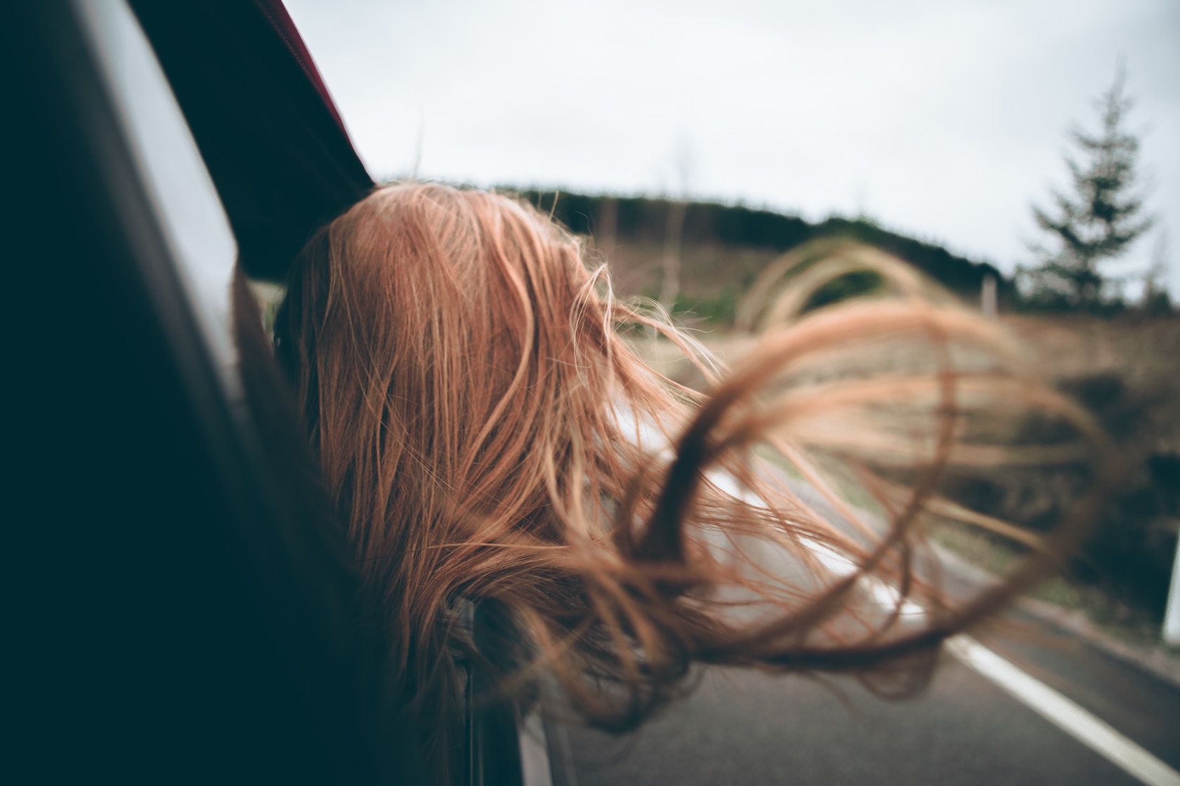Back of woman's head out car window, hair blowing in the wind, spiritual surrender