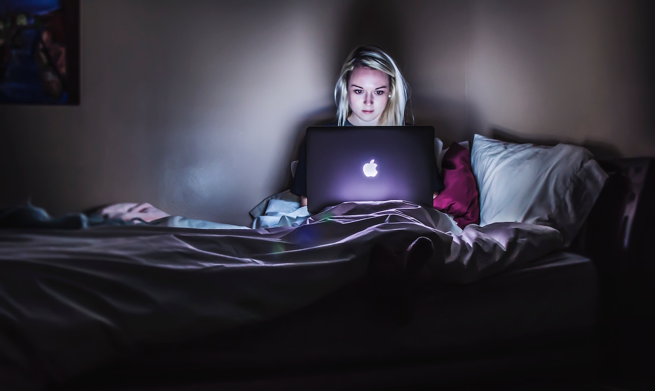 Woman in bed with laptop, finding online social media support for opioid addiction