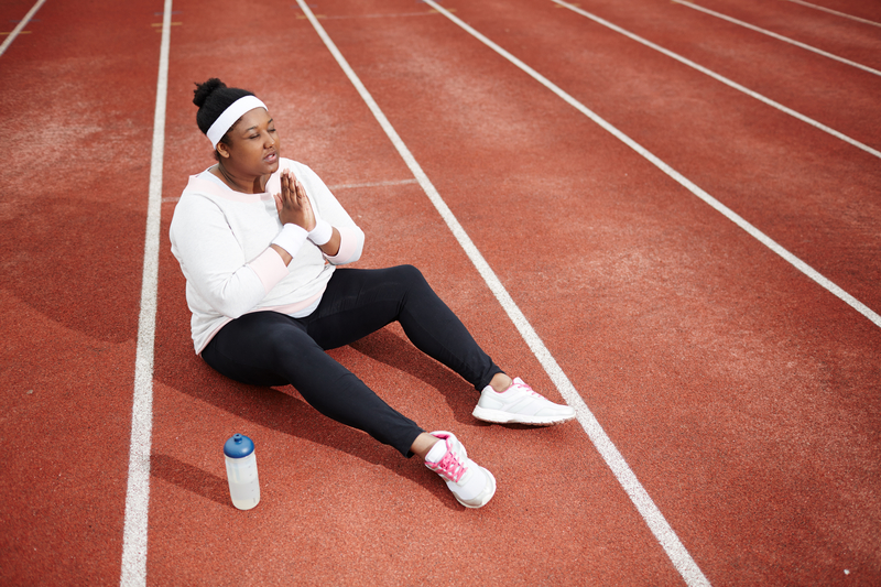 Overweight woman sitting on running track praying to her higher power