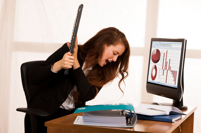 Angry woman hates her miserable job, holding keyboard above desk