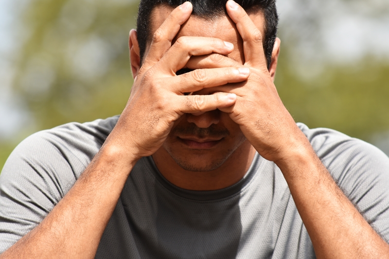 Man with head in hands, ashamed or hopeless.