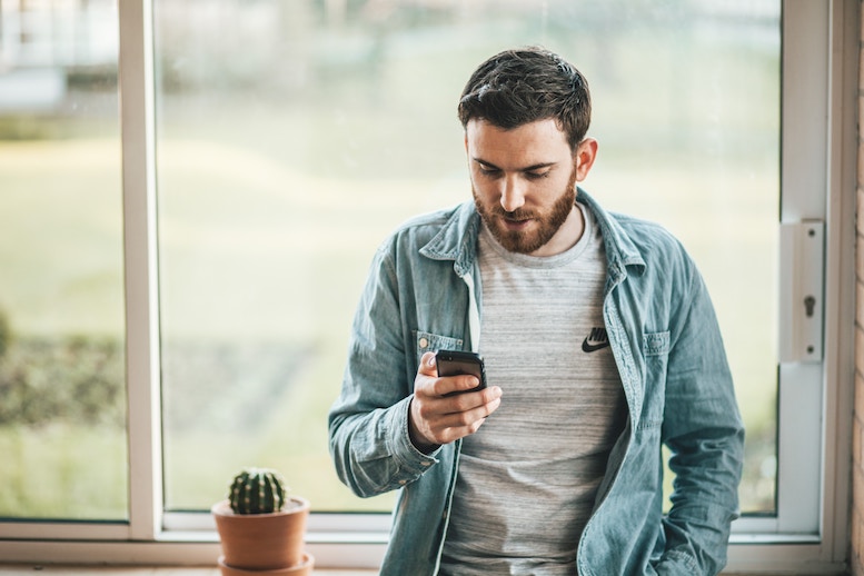 man looking at phone regretting last night's drunk text