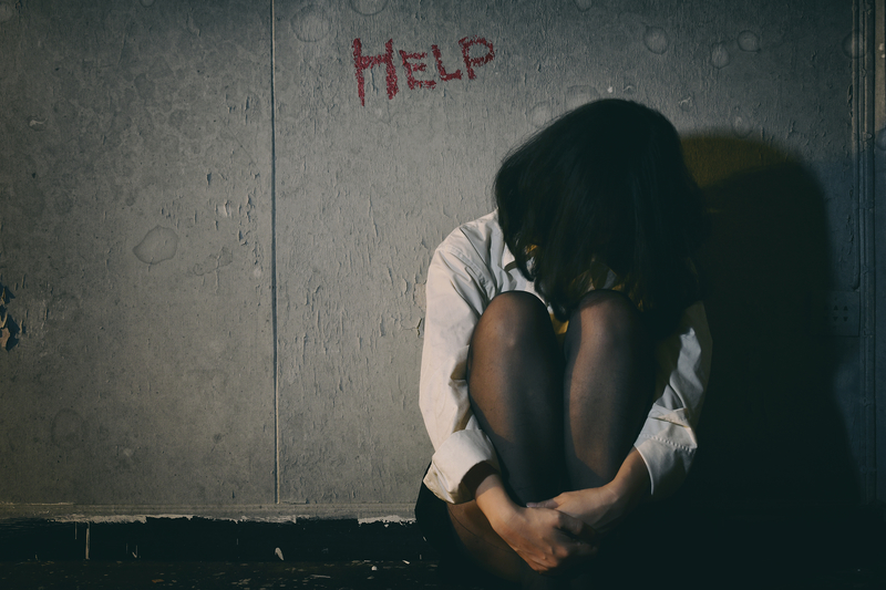 woman under word "help" written on wall