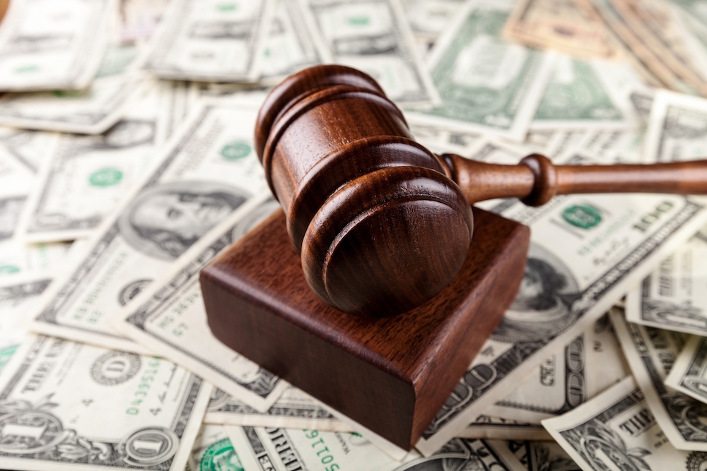 gavel sitting on top of cash from a lawsuit settlement